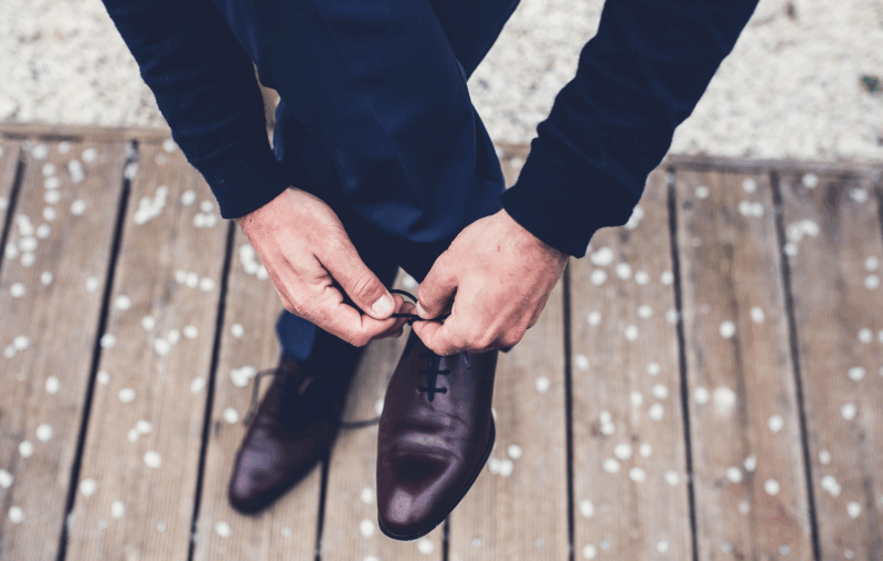 Busy professional tying dress shoes after receiving a HealthyNails™ clinical pedicure in Austin